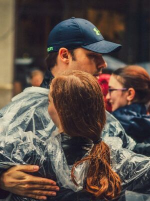 A couple in rain ponchos dancing passionately amidst a bustling New York street scene.