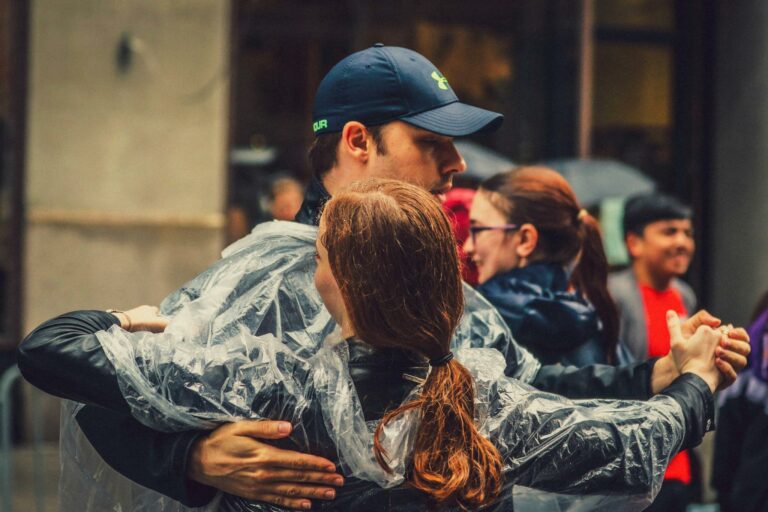 A couple in rain ponchos dancing passionately amidst a bustling New York street scene.
